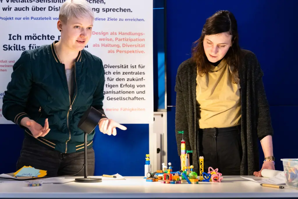 Zwei junge Frauen präsenieren etwas mit Lego Gebasteltes