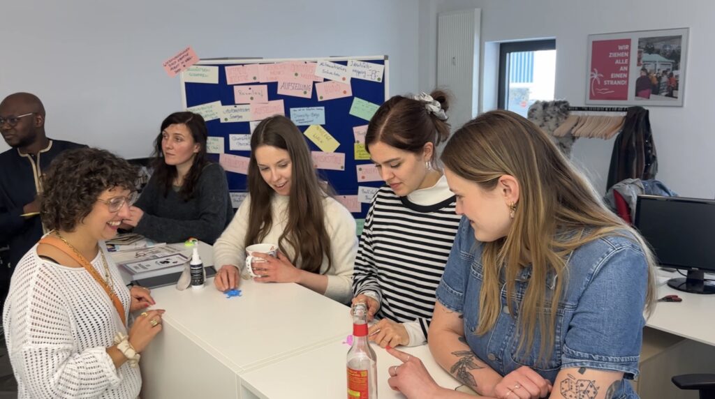 6 Personen stehen um einen Hochtisch und sprechen miteinander während sie die innovativen Methoden ausprobieren.